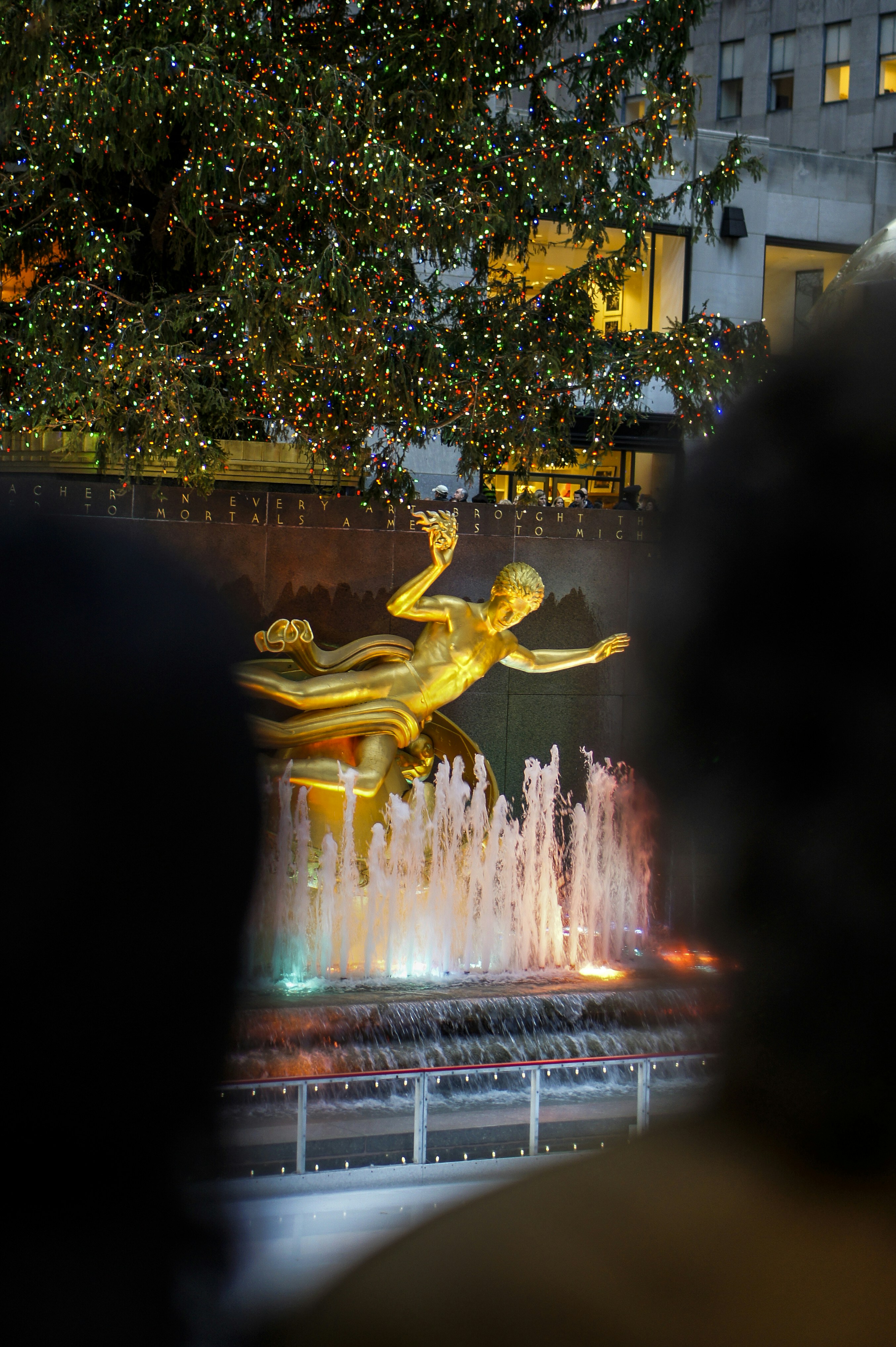 Golden prometheus statue with illuminated fountain at night