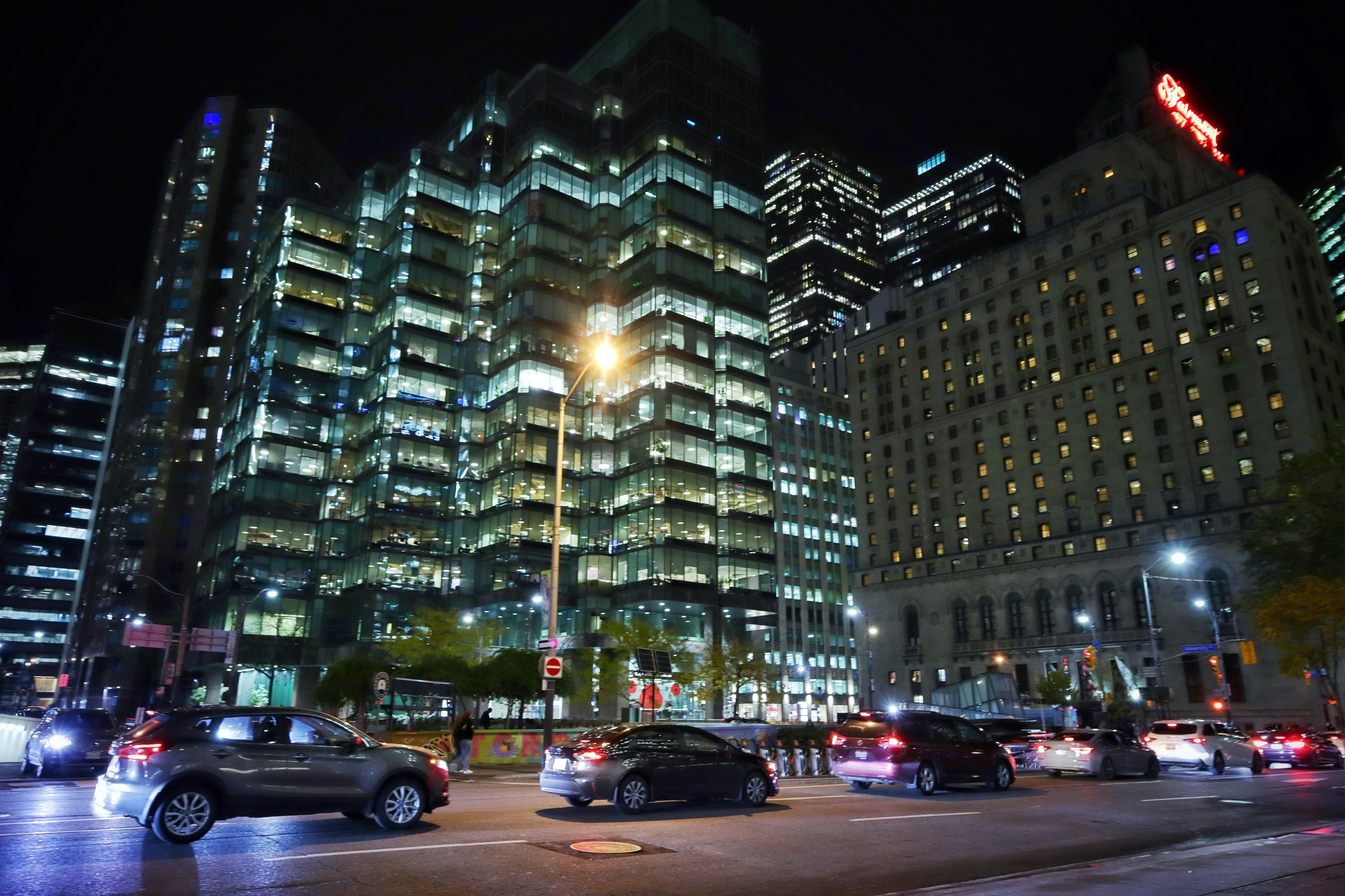 Cars drive on a street in a city at night.