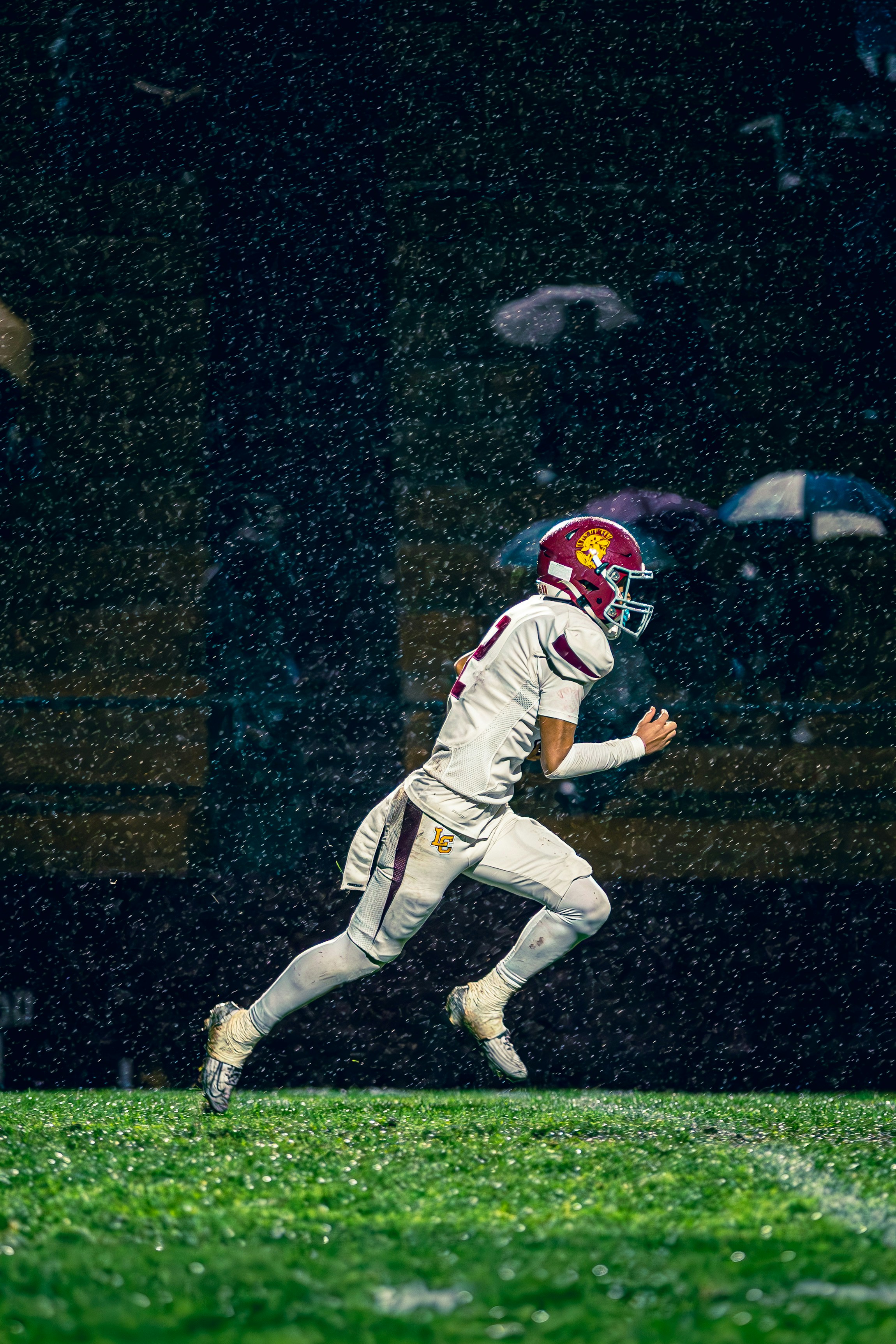 Football player running on field during heavy rain