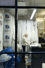Woman working in a dry cleaning establishment with garments.
