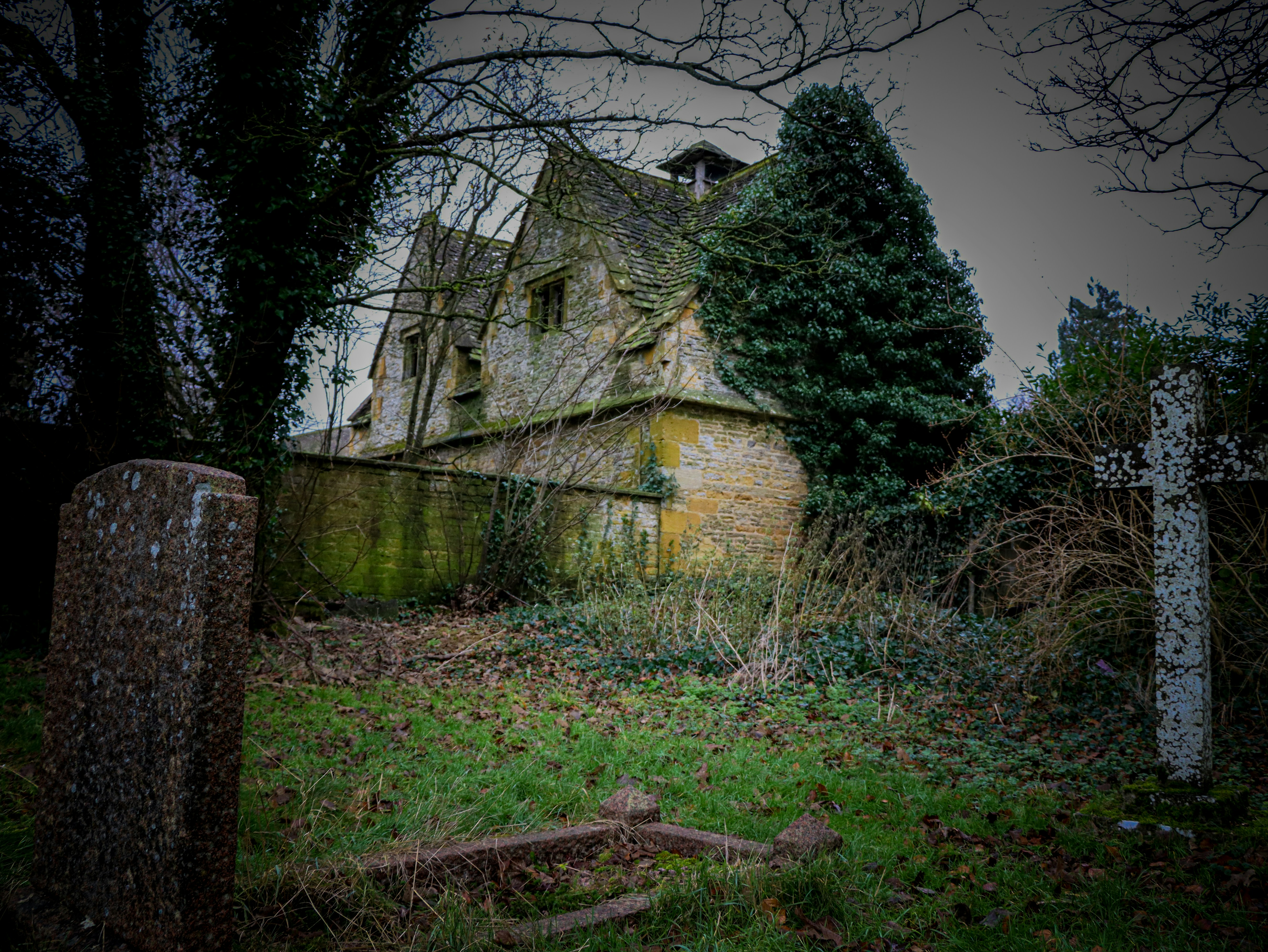 Abandoned stone house with overgrown garden and graves