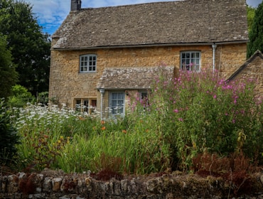 Stone cottage with blooming flowers in front.