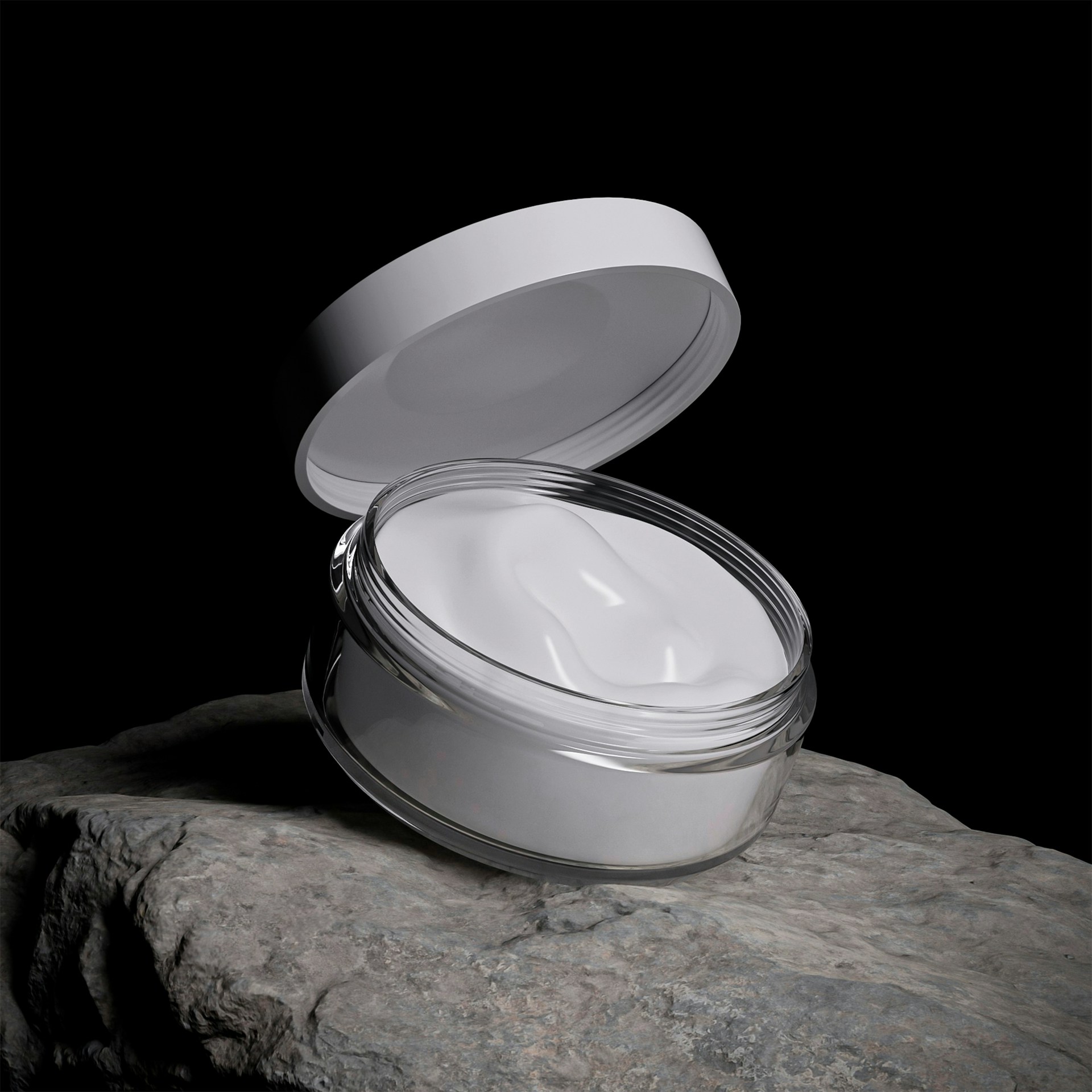 White cream in an open jar on a rock.