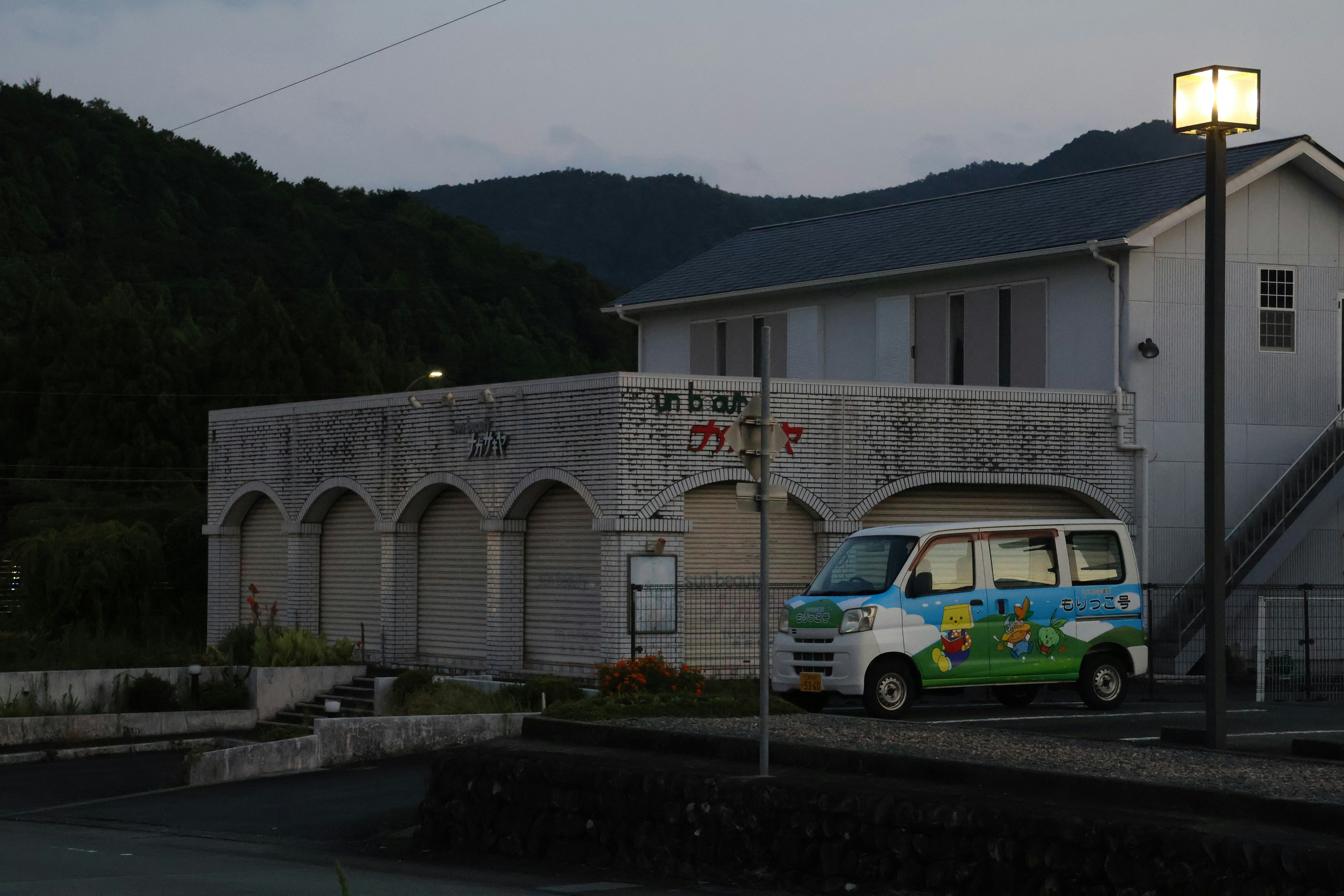 A small van parked outside a building at dusk.
