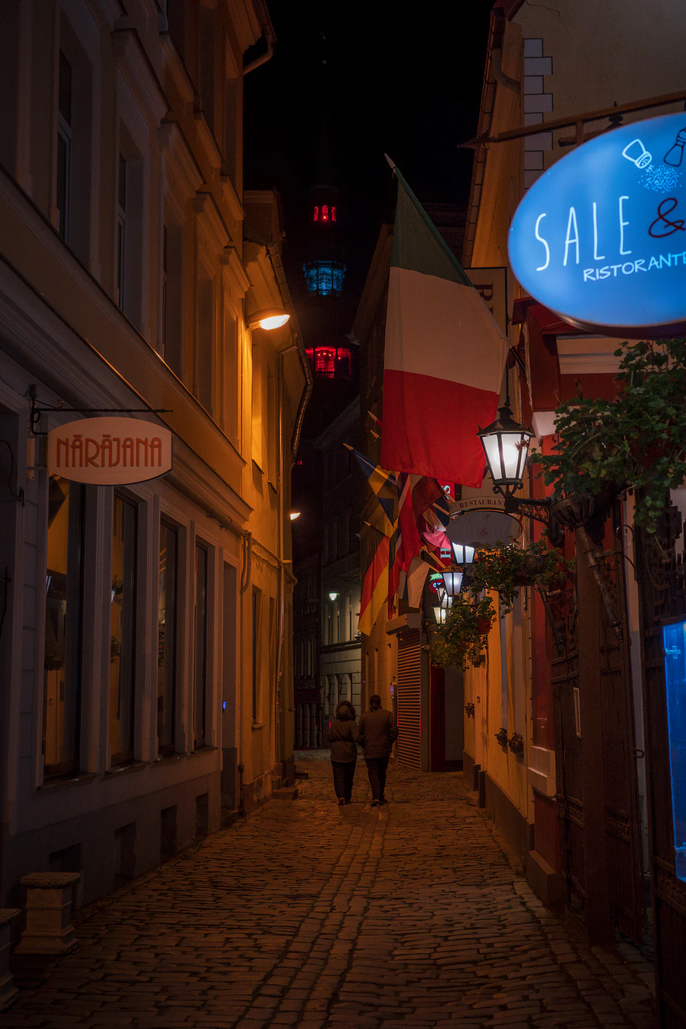 A narrow street in the evening, a bar sign lit