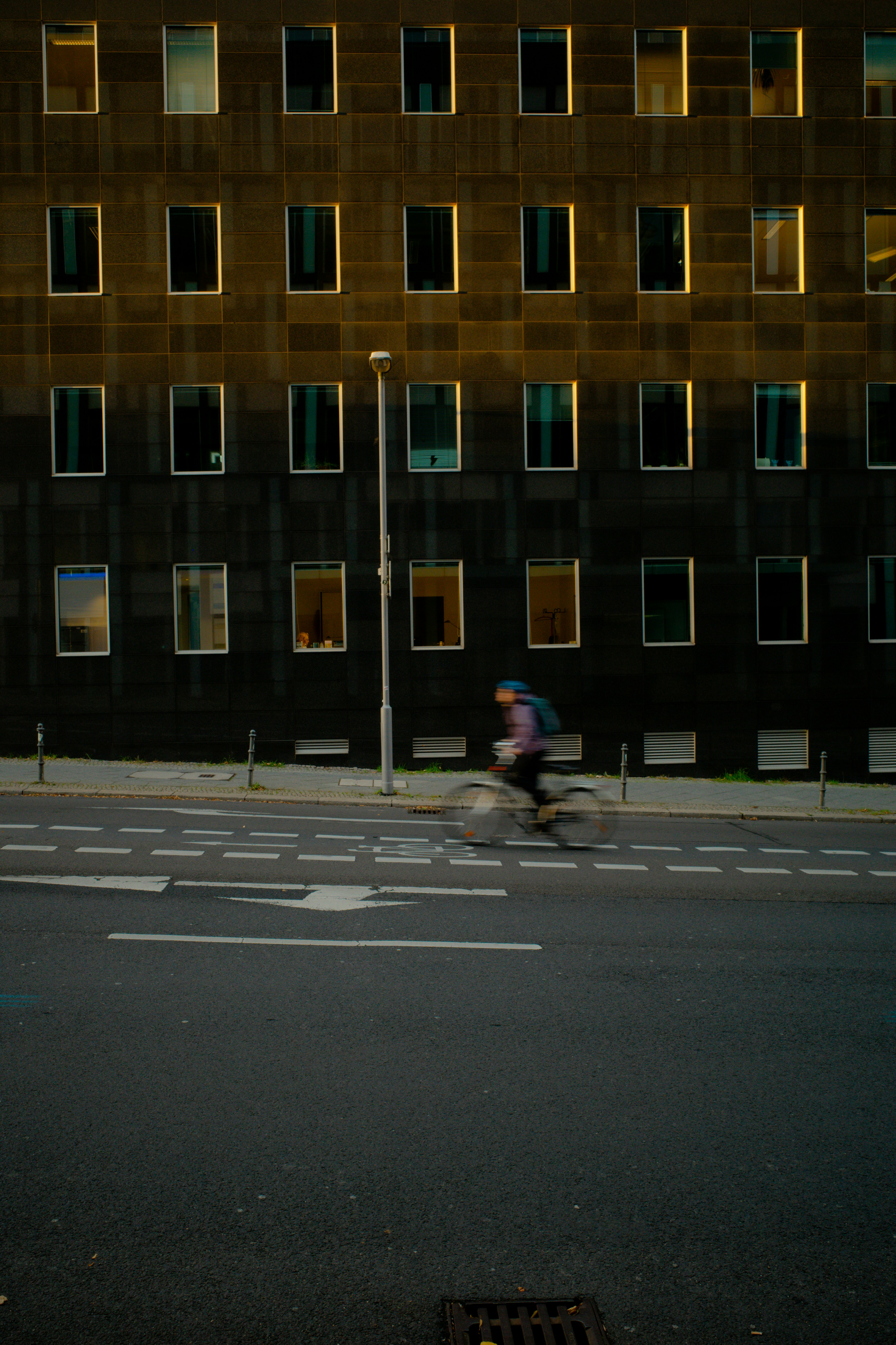 Cyclist rides past building with many windows