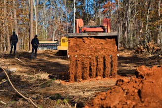 Excavator digging dirt with two people watching