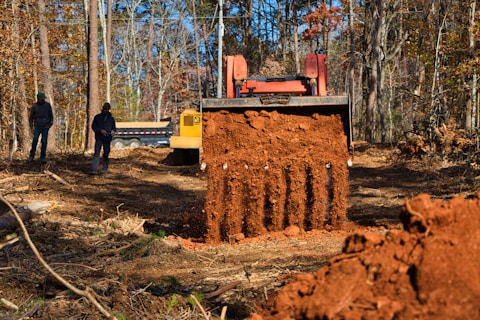 Excavator digging dirt with two people watching