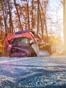 Orange kubota skid steer loader on gravel road