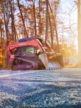 Orange kubota skid steer loader on gravel road