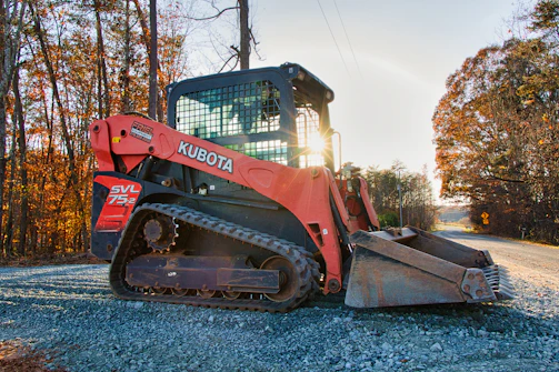 Orange kubota track loader parked on gravel road.