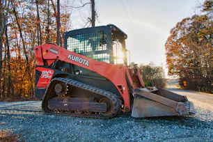 Orange kubota track loader parked on gravel road.