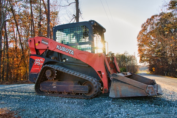 Orange kubota track loader parked on gravel road.