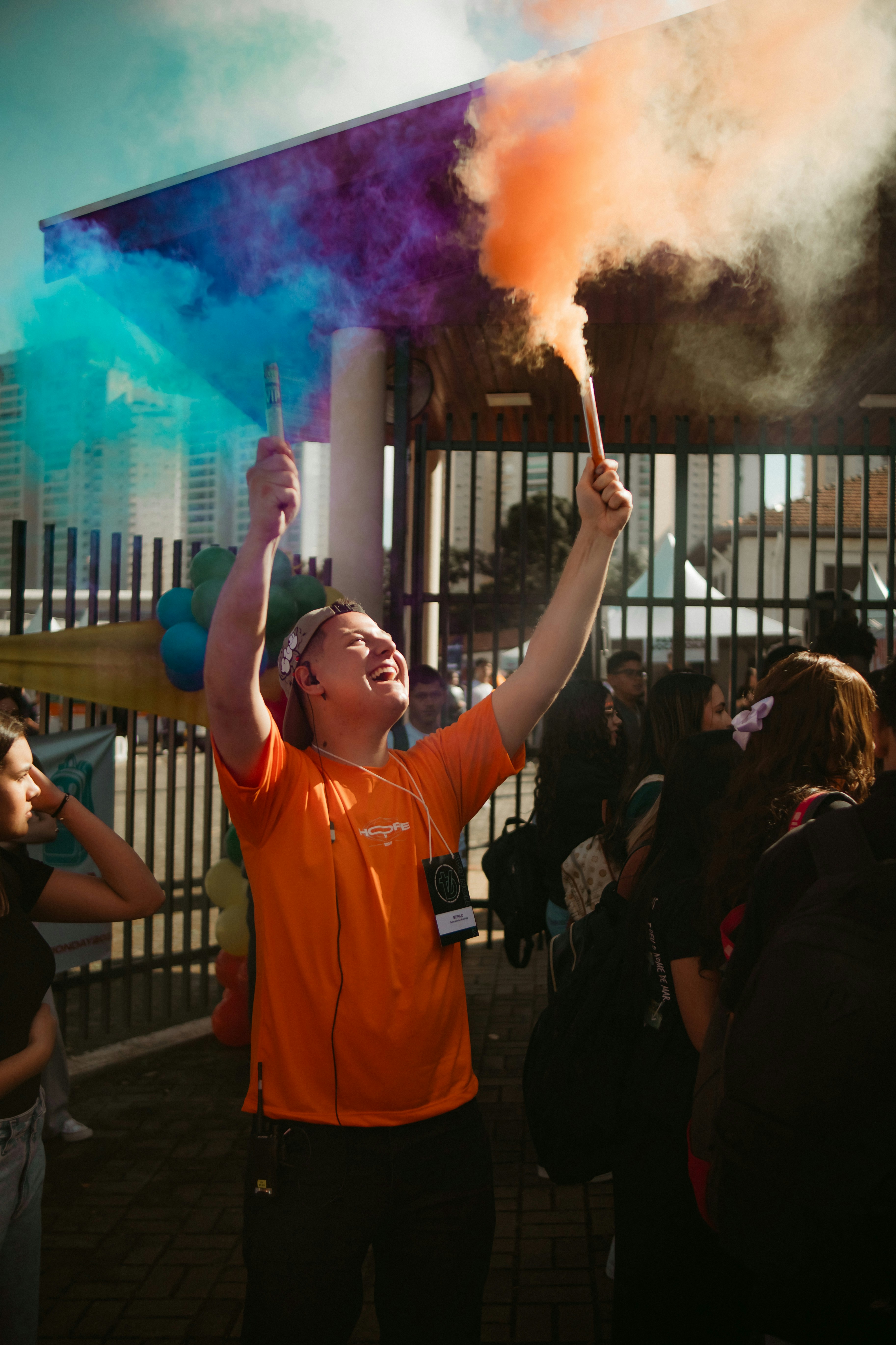 Person holding colorful smoke bombs at an outdoor event.