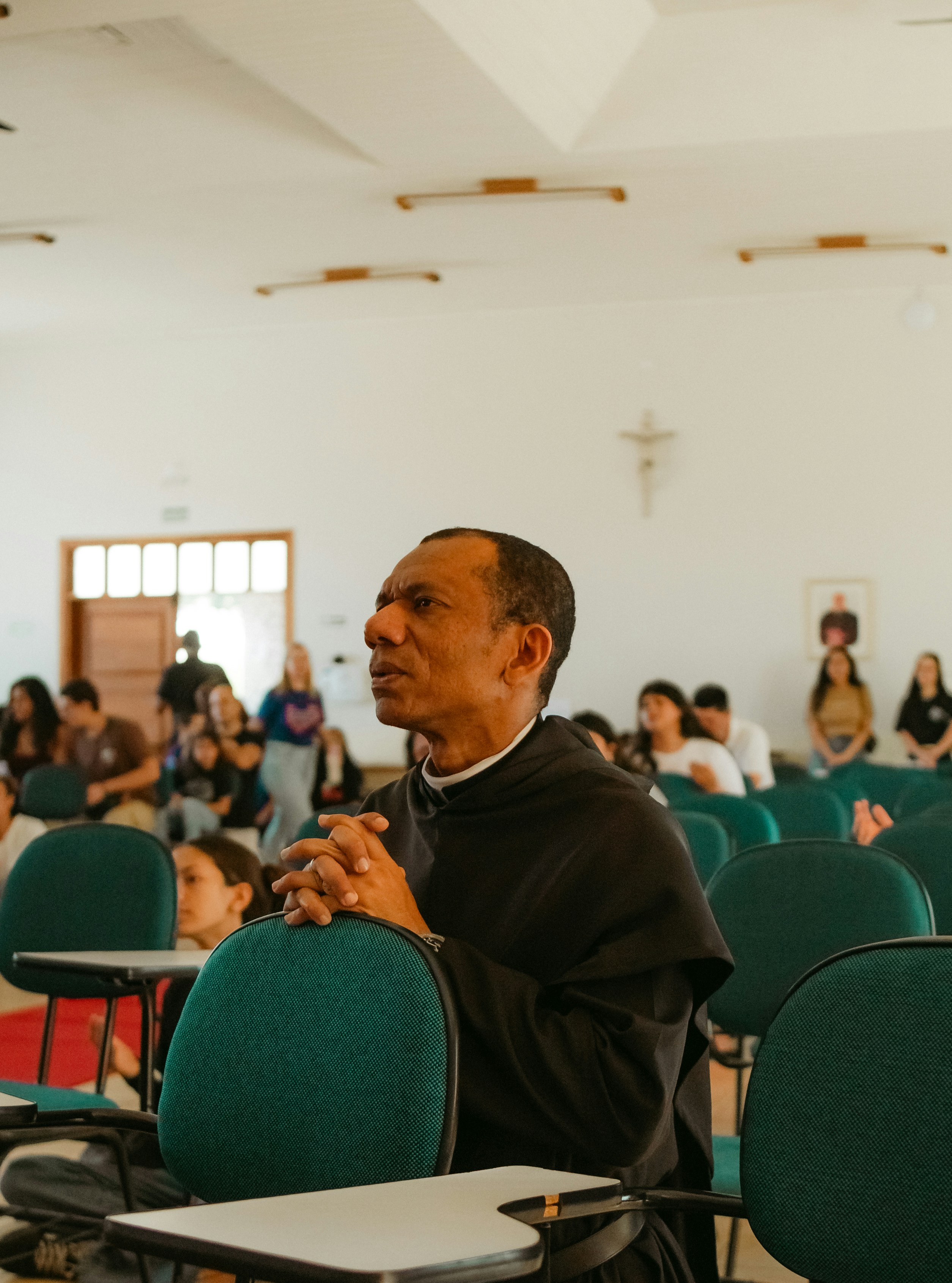 Man in religious habit praying in classroom