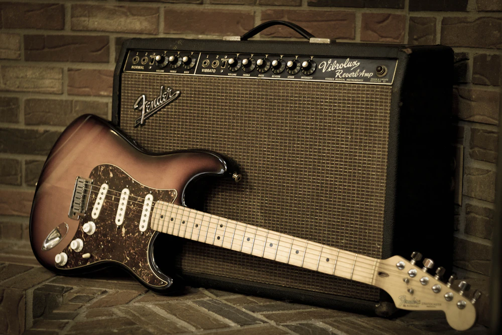Stratocaster-style guitar resting against a vintage amplifier