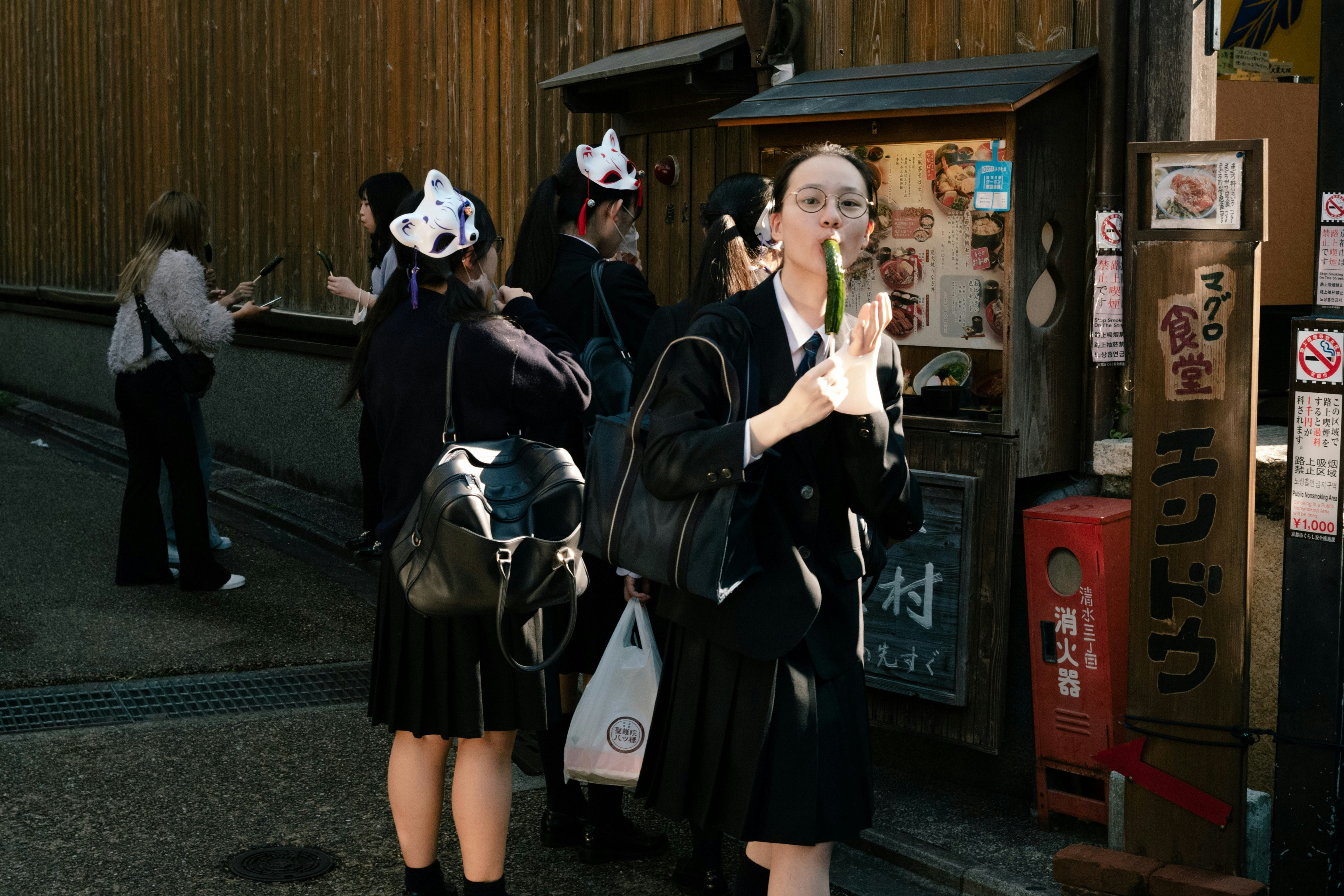 Students in uniform eating snacks from a street vendor.