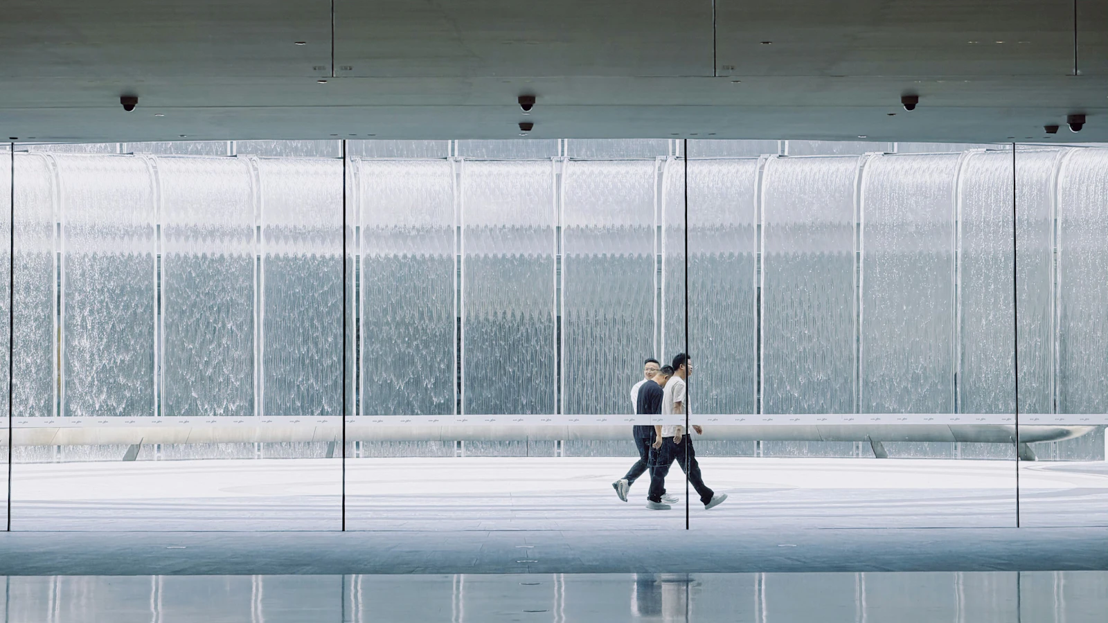 Two people walking through a bright, minimal corridor