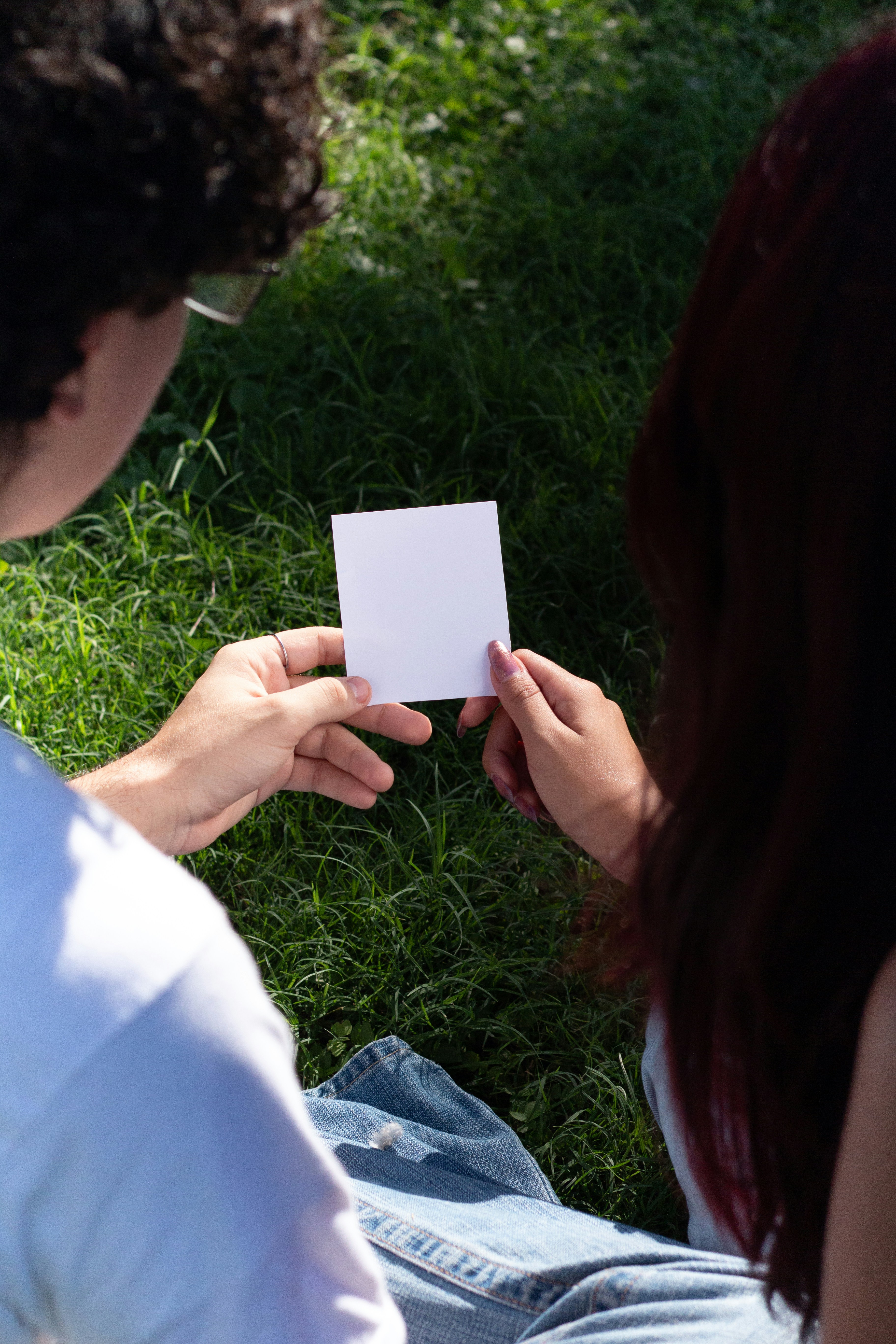 Two people holding a blank square card outdoors