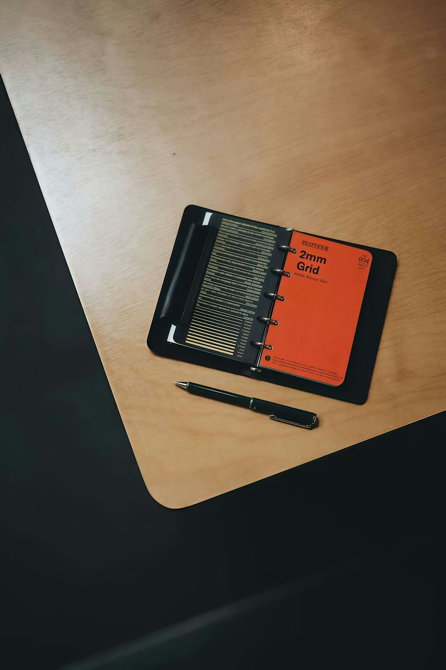 Grid notebook and pen resting on a wooden desk