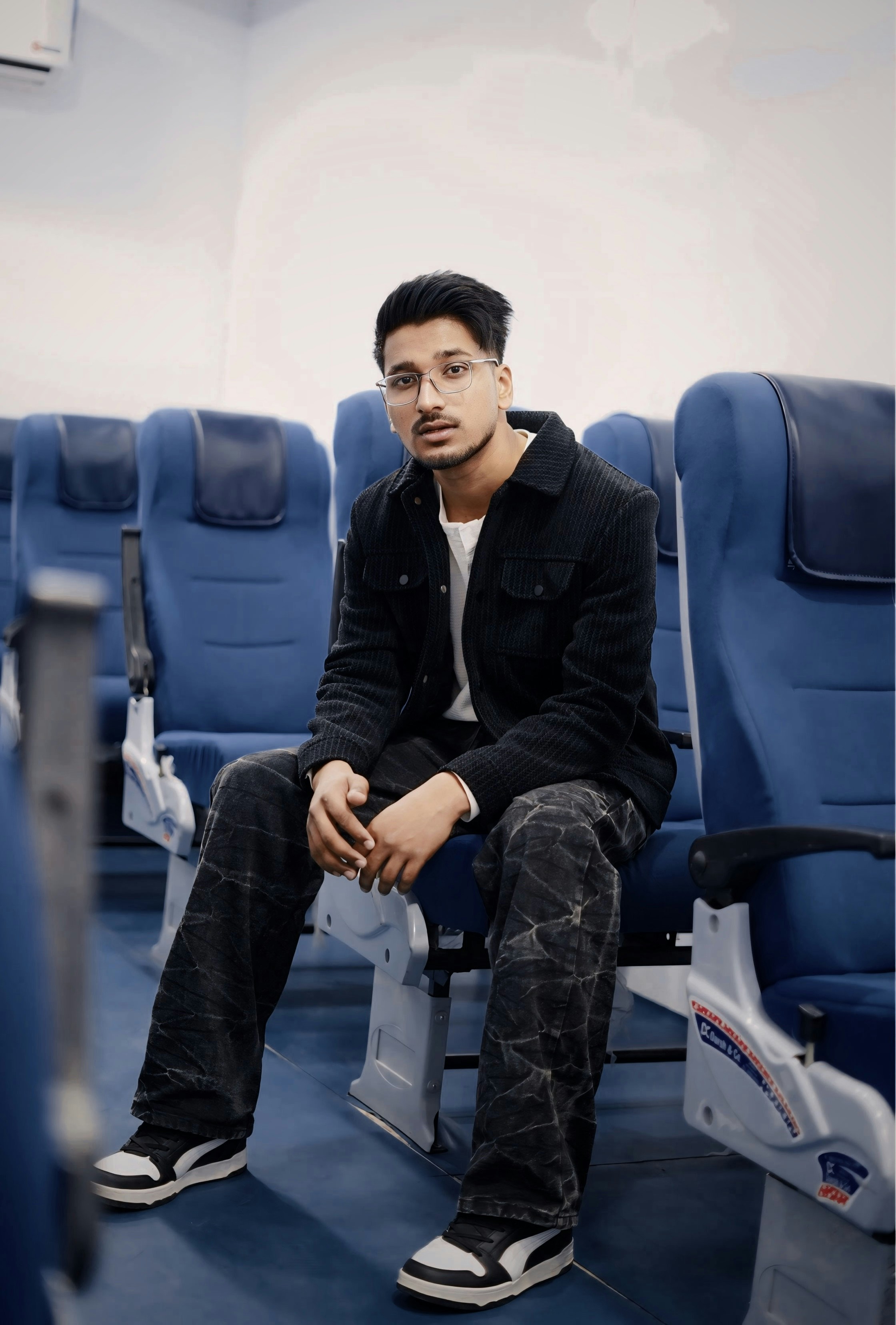 Young man sitting on airplane seats wearing jacket