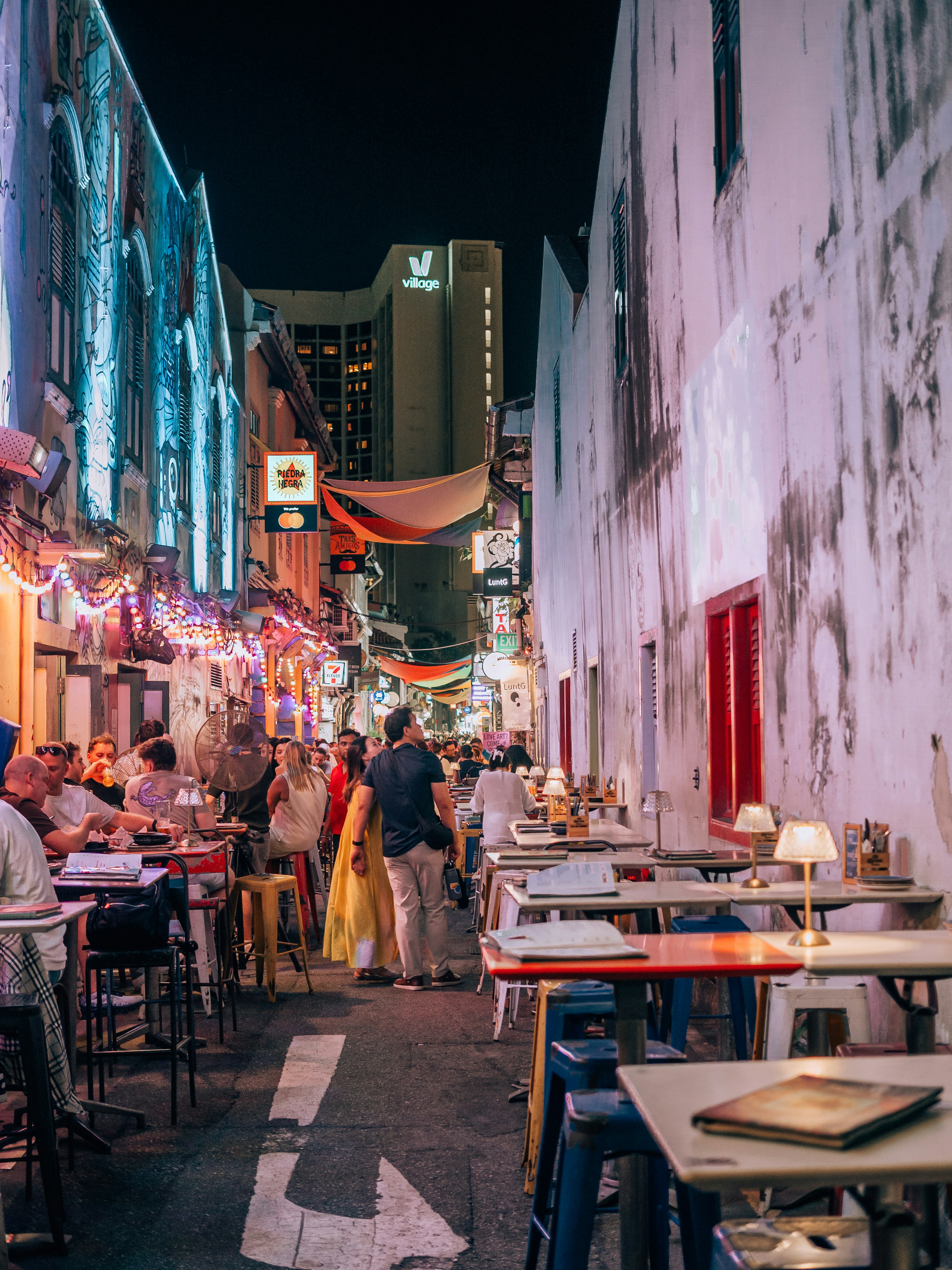 People dining at outdoor tables on a vibrant city street.