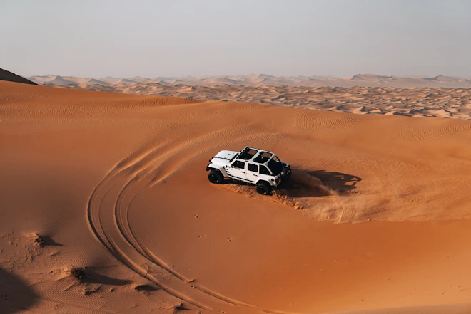 White suv driving on sand dunes