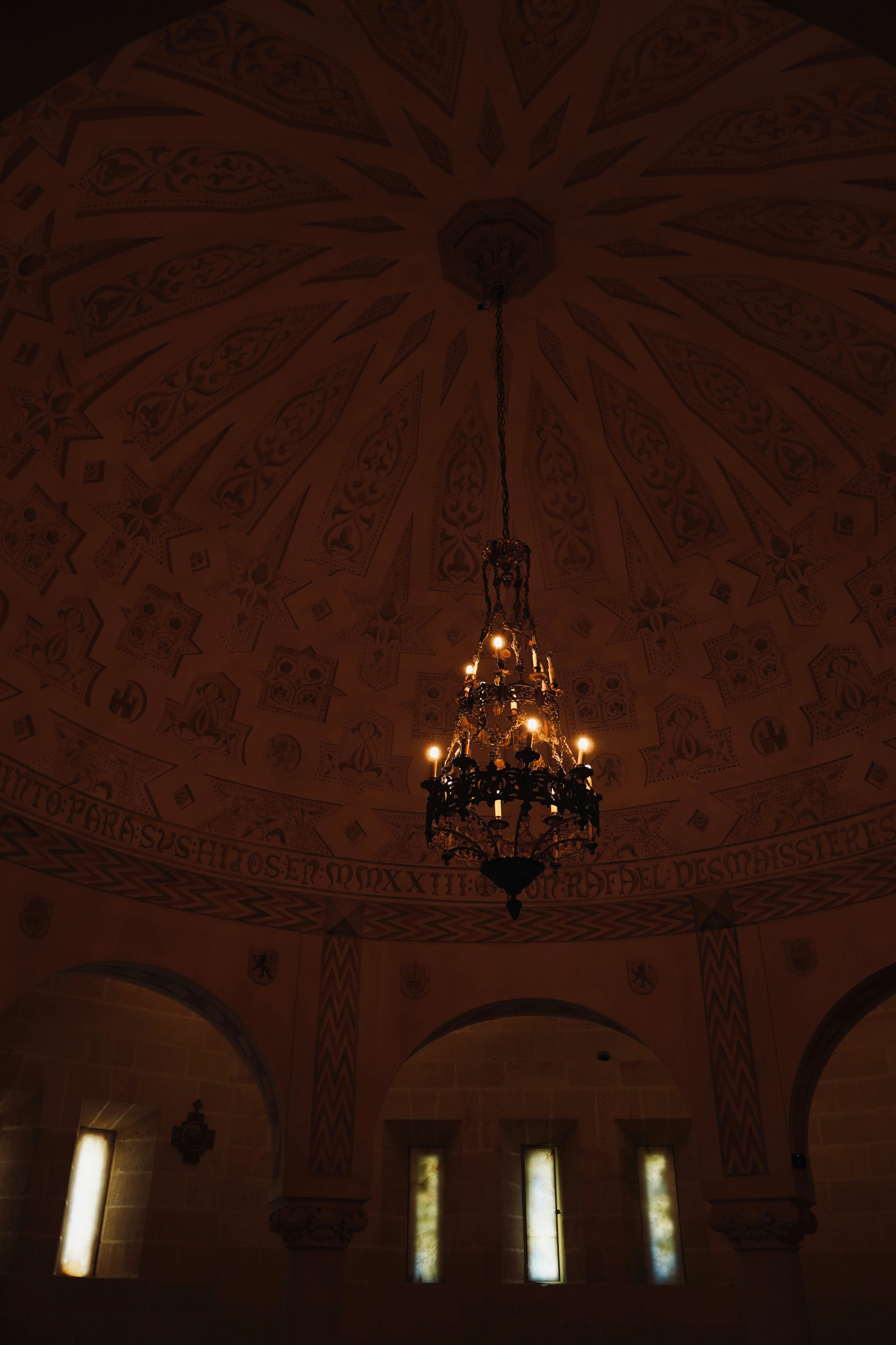Ornate chandelier hangs in a domed room.