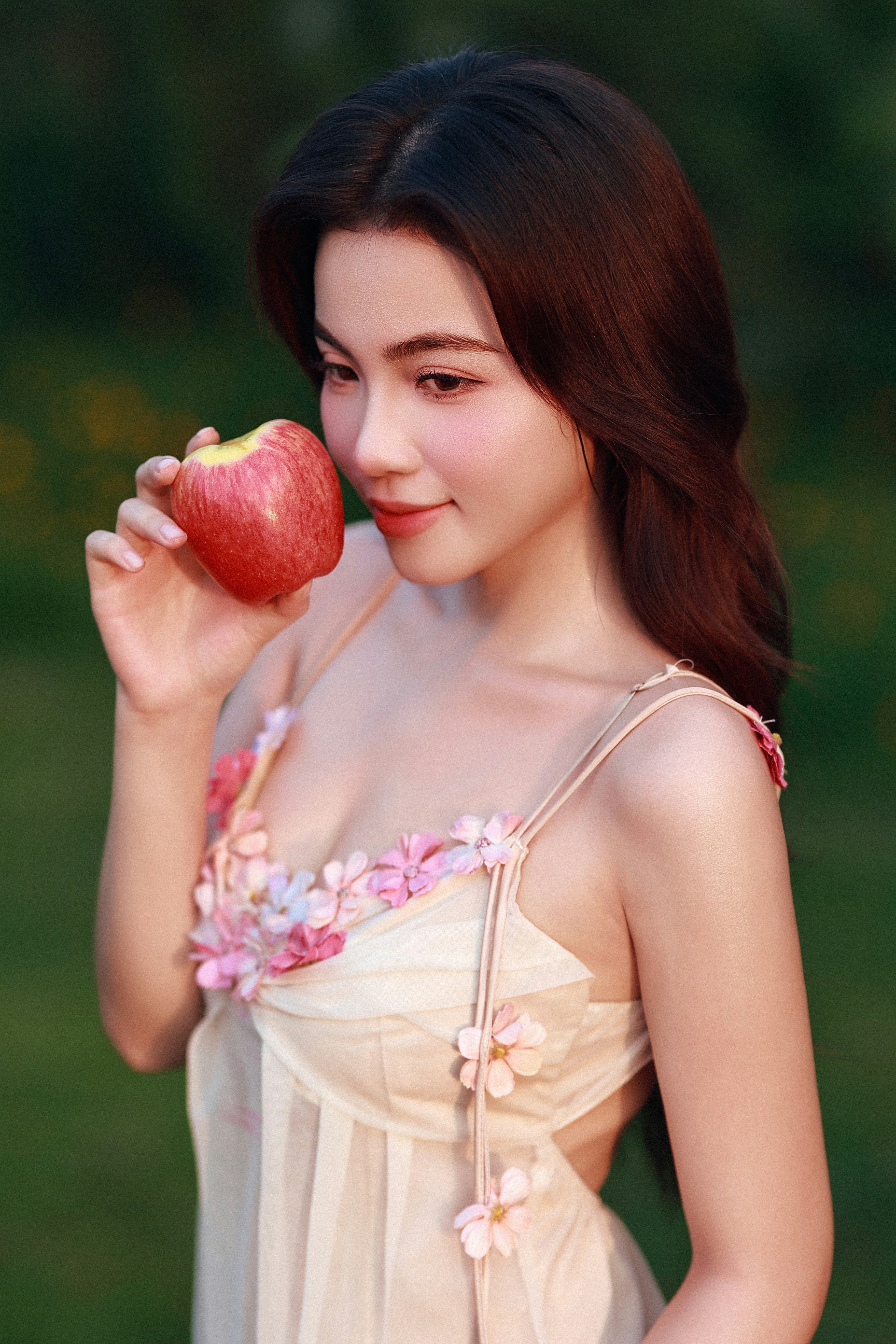 Woman holding a red apple in a garden