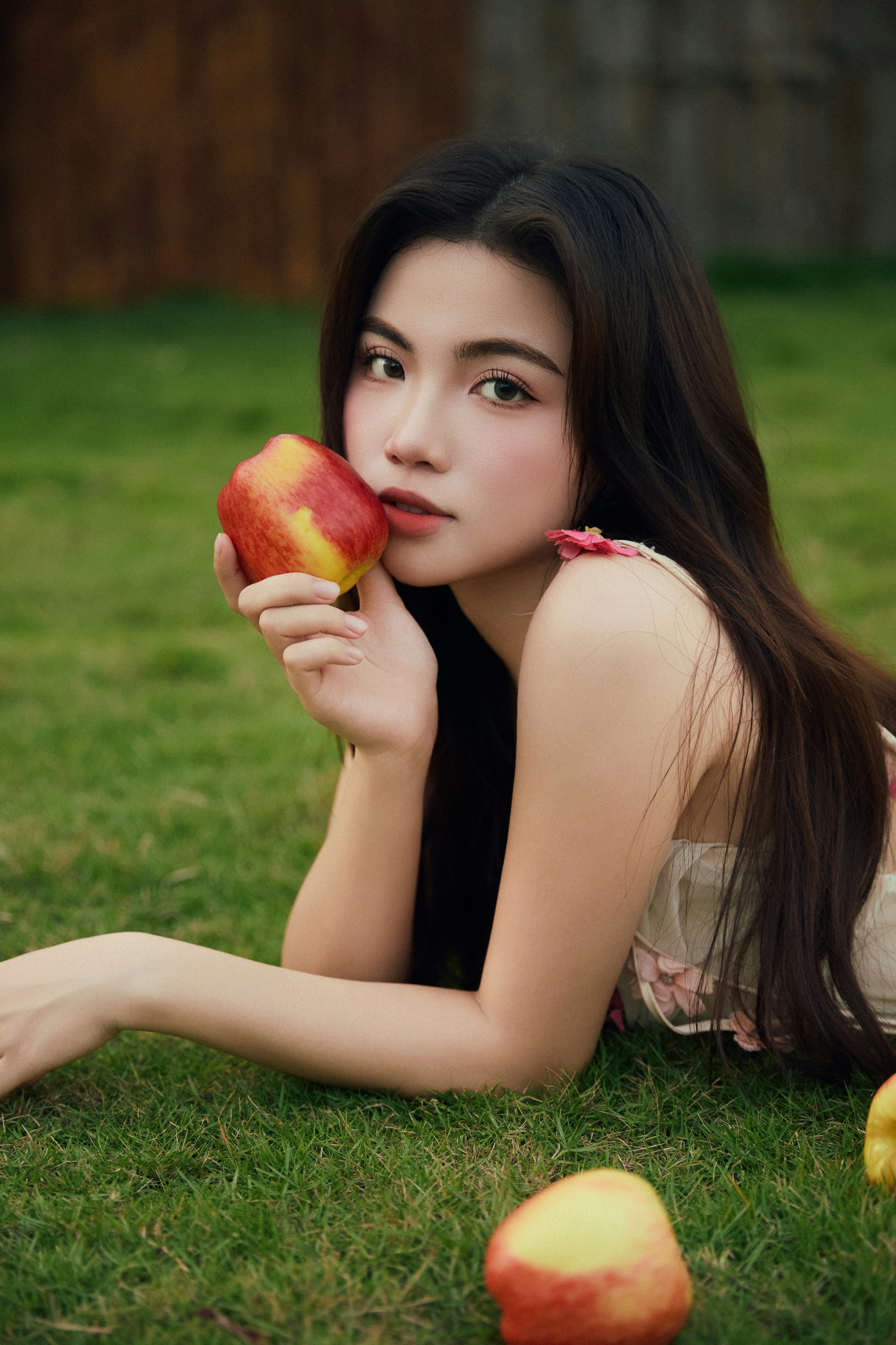 Young woman holding an apple on grass
