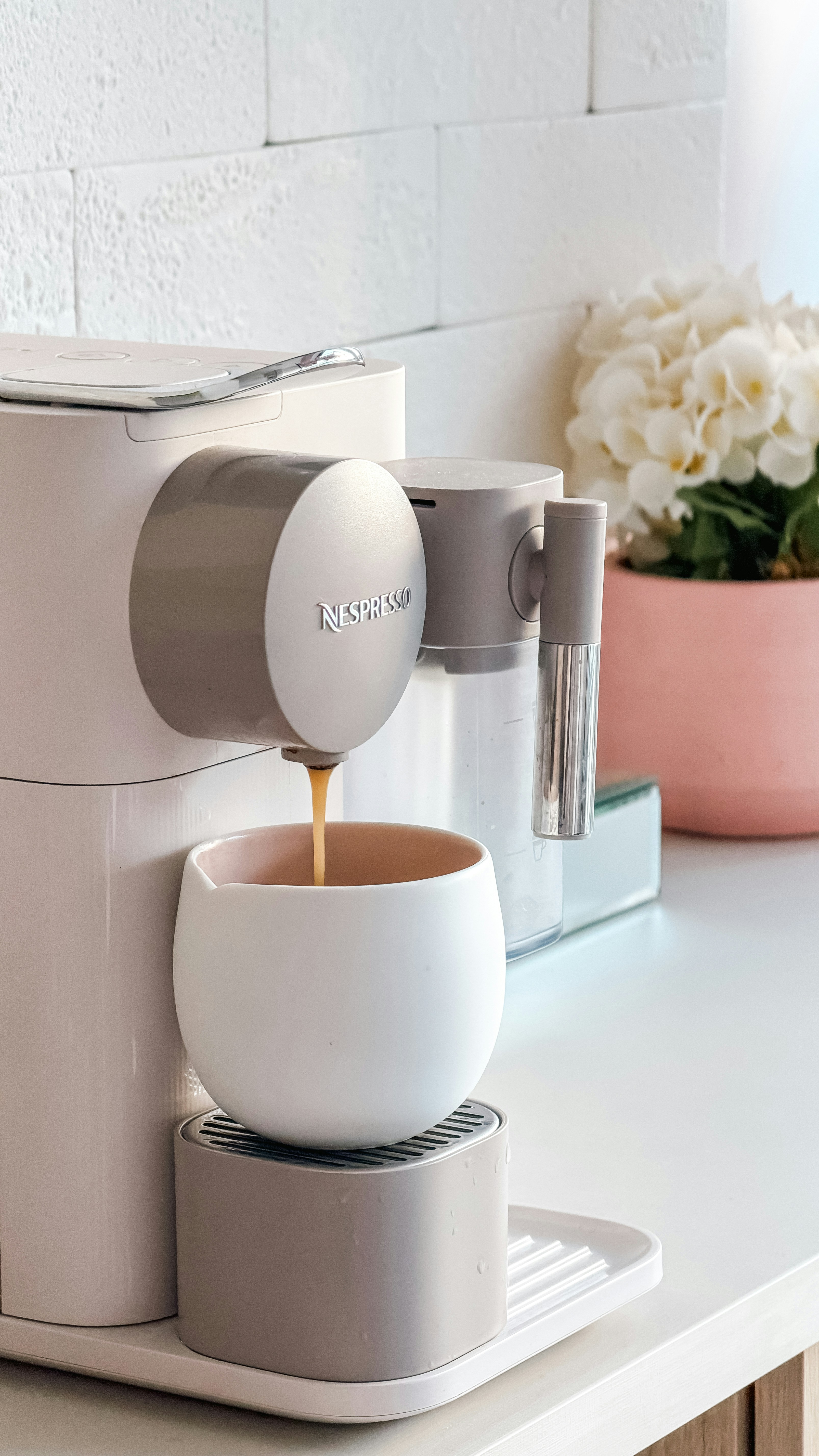 Coffee pouring into a white cup from a machine.