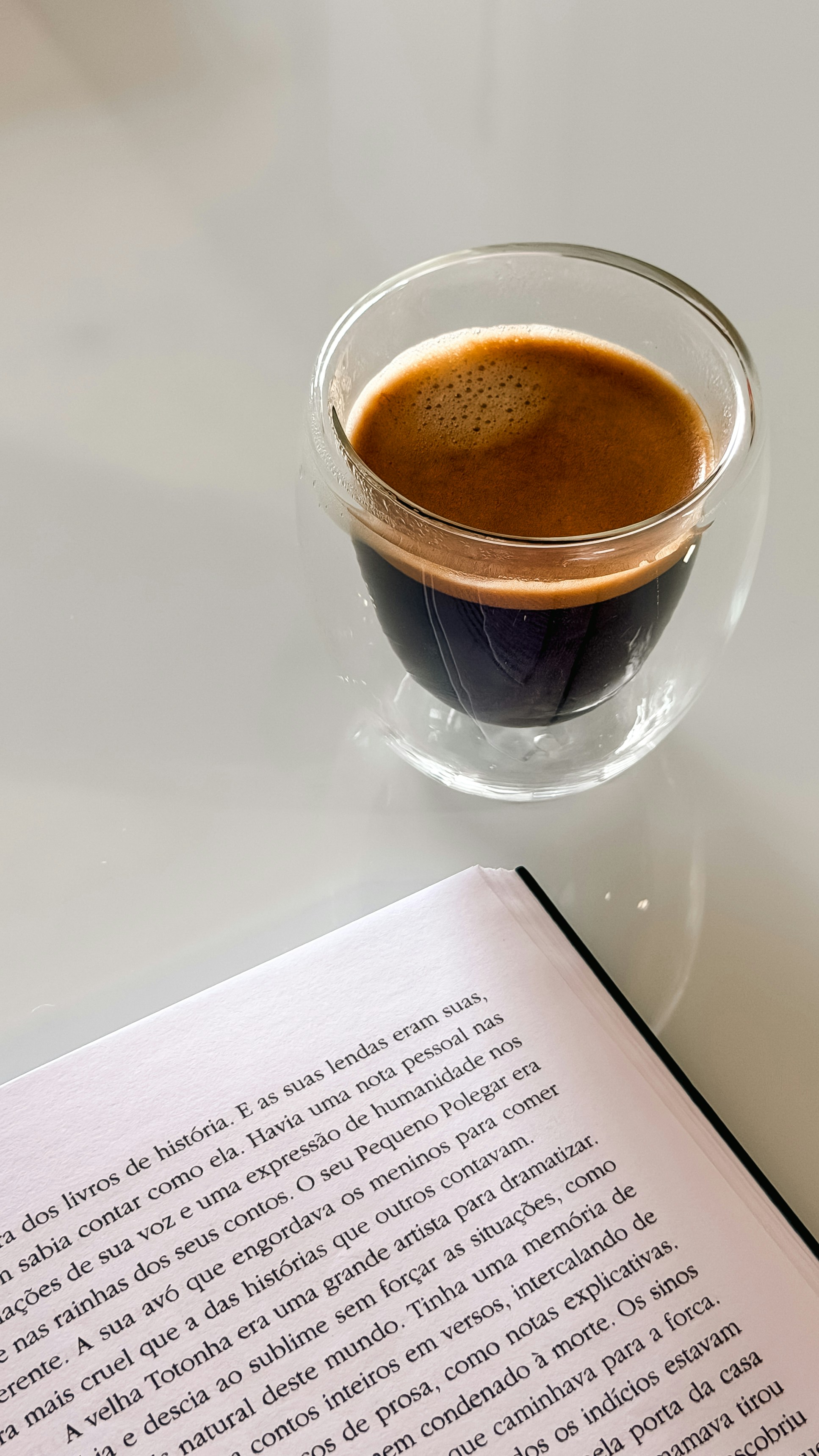 Espresso coffee and an open book on a white table.