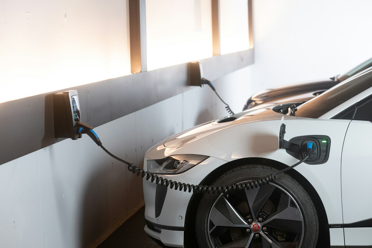 Weißes Elektroauto an einer Wandladestation