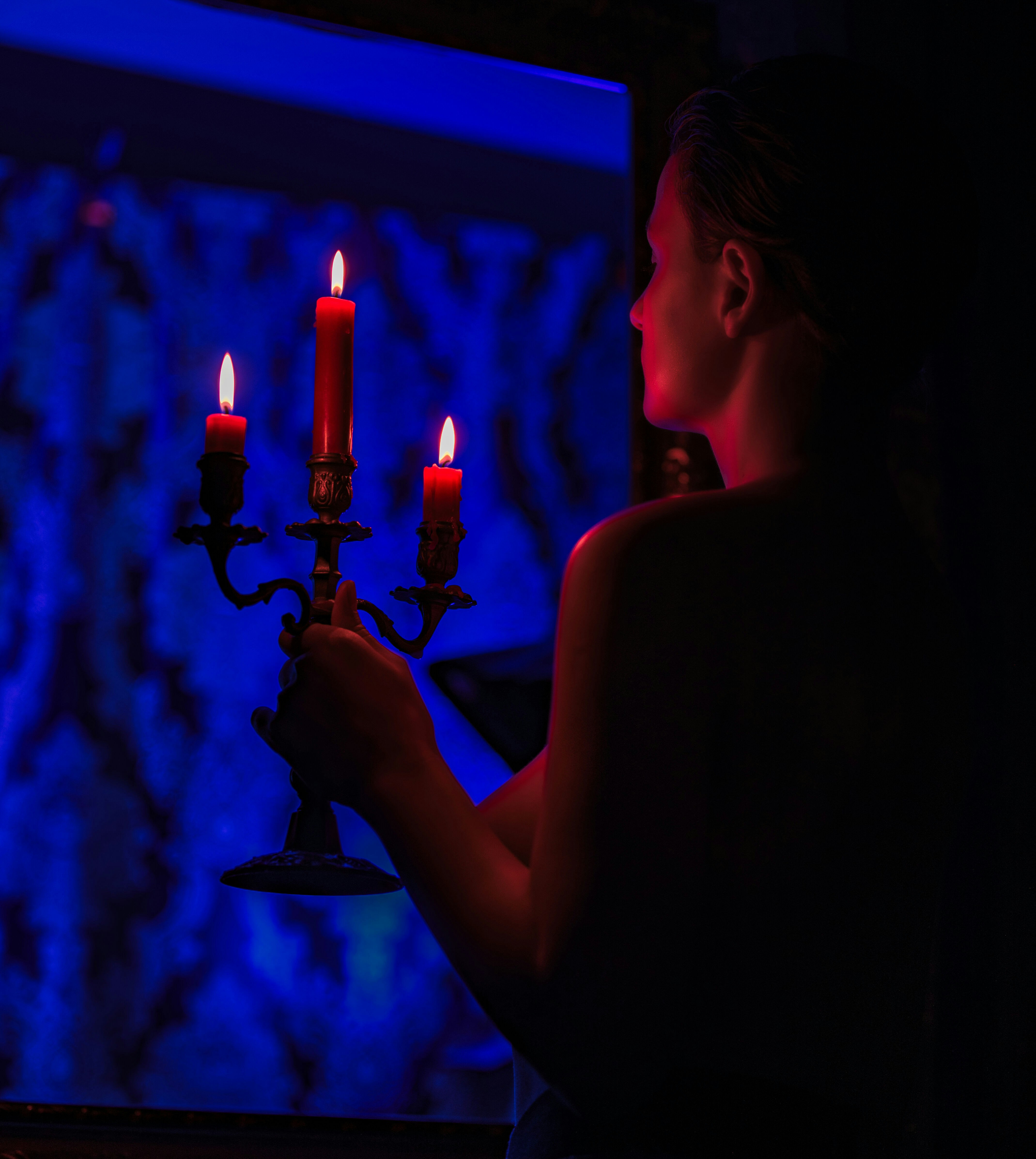 Mujer sosteniendo un candelabro con tres velas encendidas.