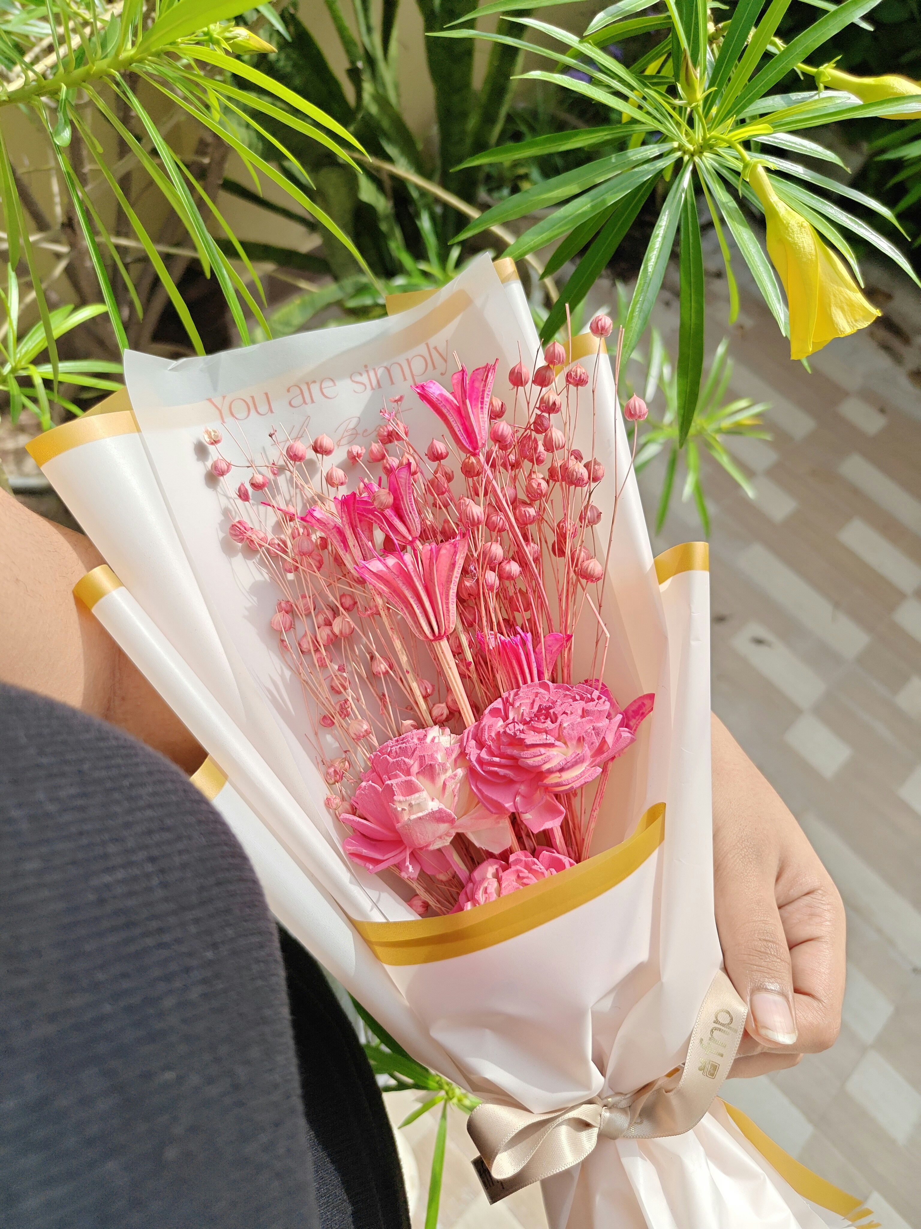 A hand holding a small bouquet of pink flowers.