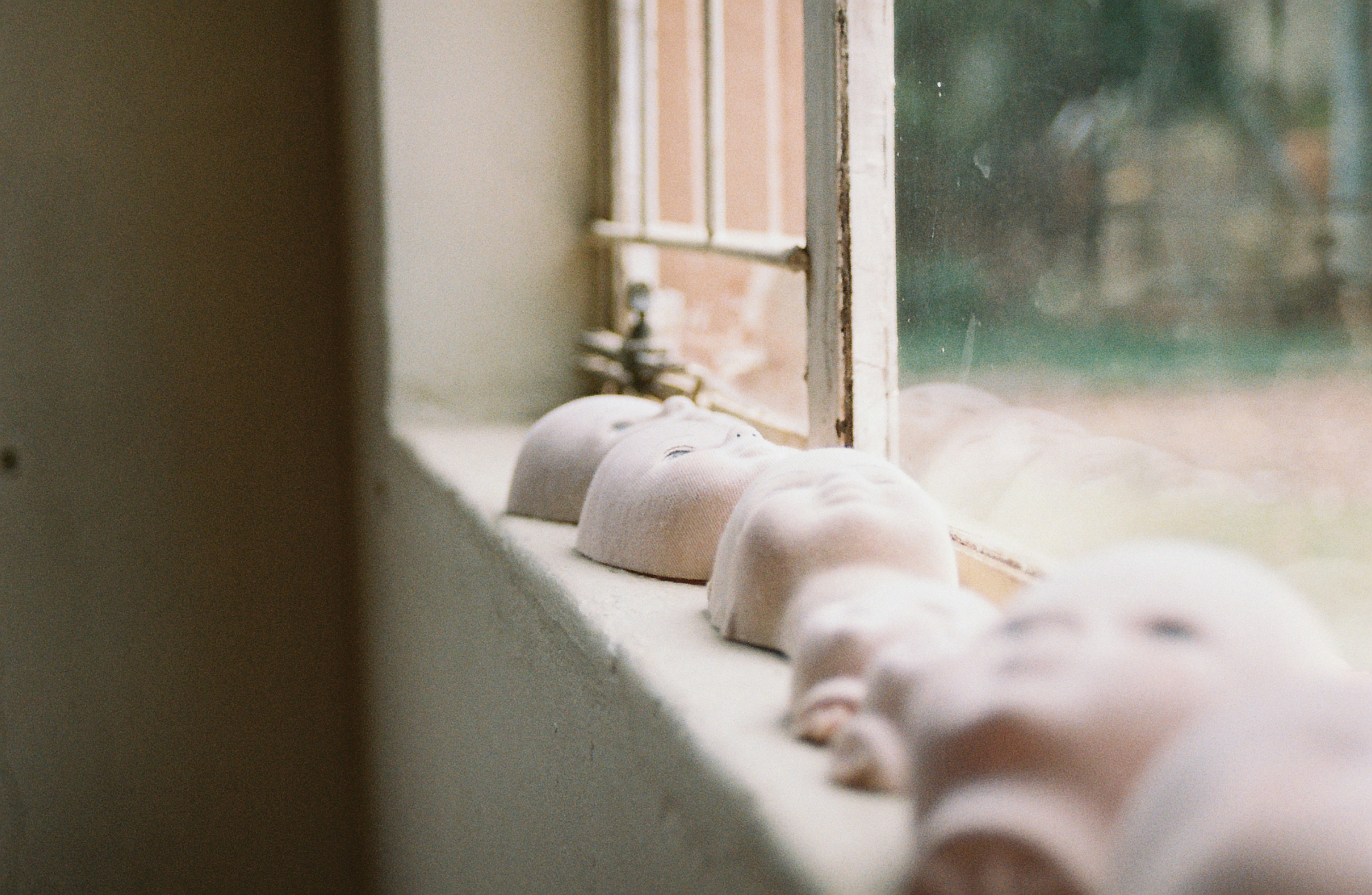 Row of doll heads on a windowsill