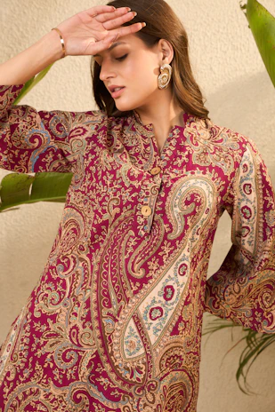 Woman in a patterned maroon dress with bell sleeves.