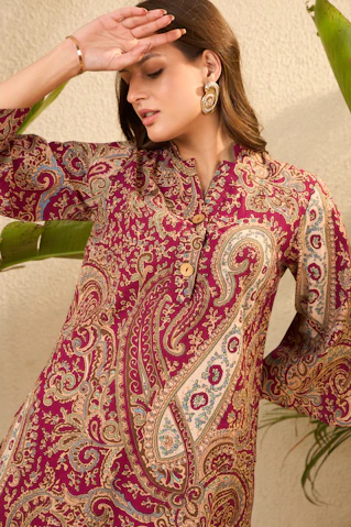 Woman in a patterned maroon dress with bell sleeves.