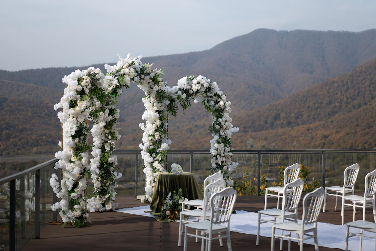 Outdoor wedding ceremony setup with floral arch and mountain backdrop