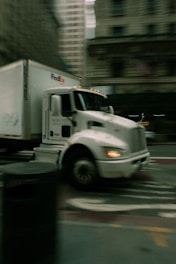 A white fedex truck driving on a city street