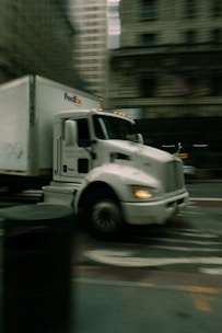 A white fedex truck driving on a city street
