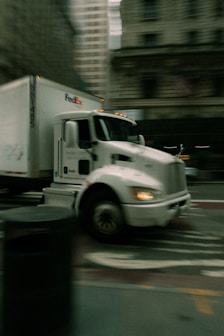 A white fedex truck driving on a city street