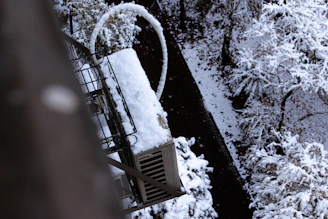 Snow covered industrial equipment next to trees