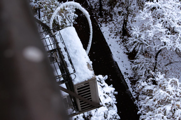 Snow covered industrial equipment next to trees