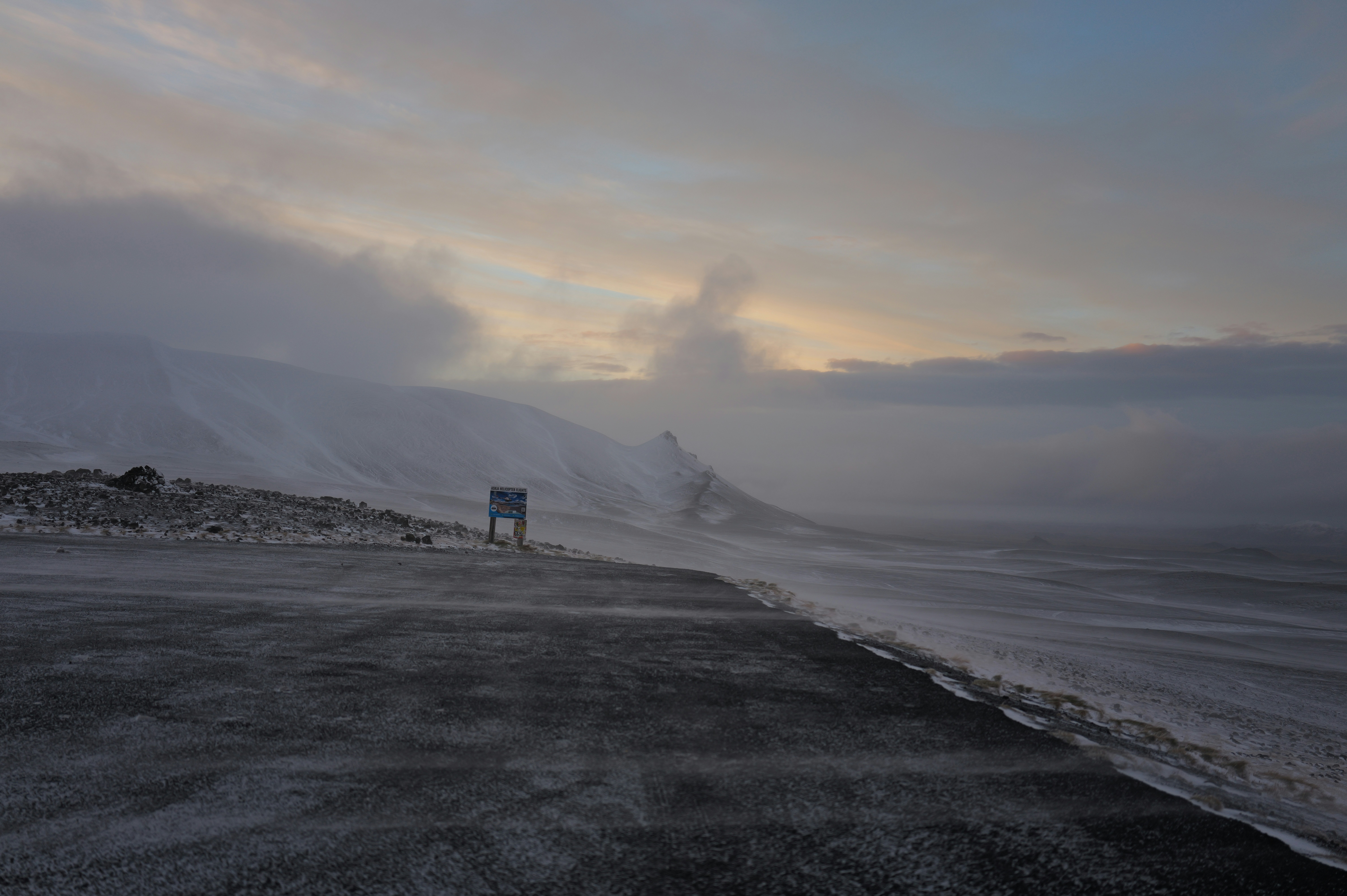 Misty coastal landscape with snow-covered mountains.