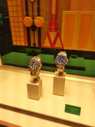 Two luxury watches displayed in a store window.