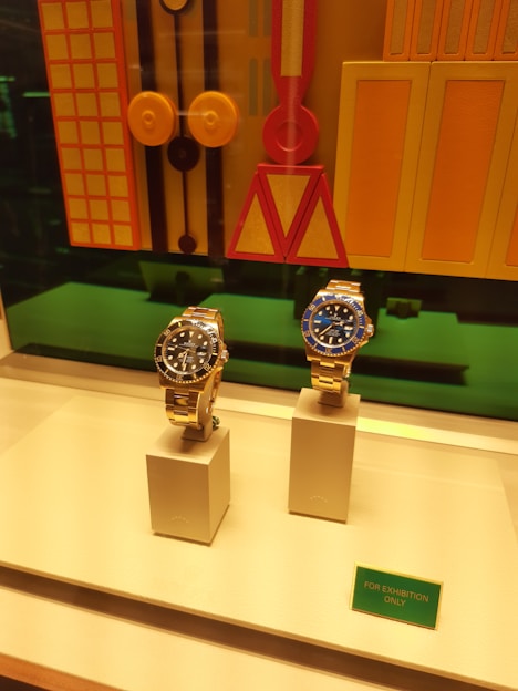Two luxury watches displayed in a store window.