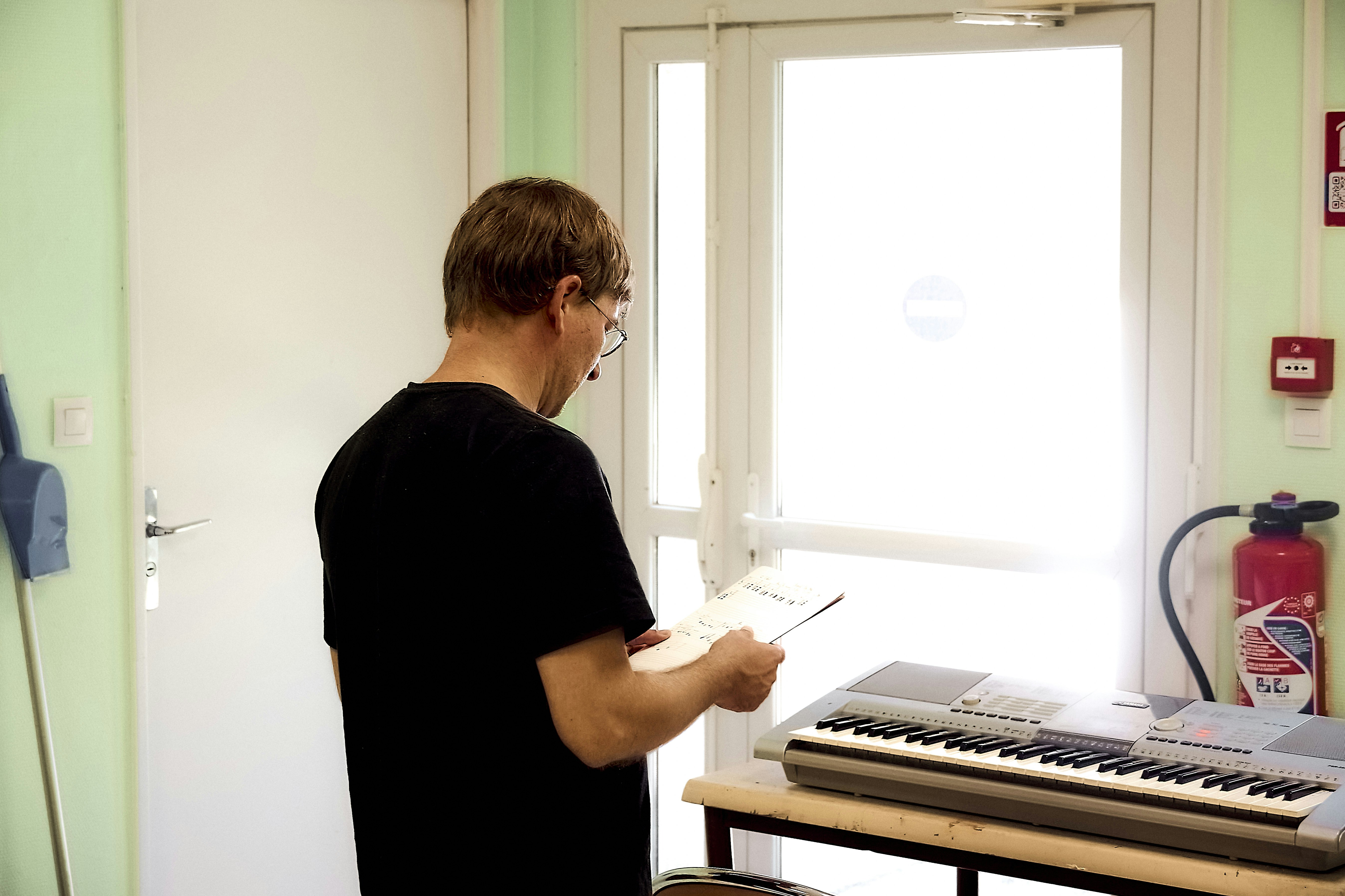 Man reading sheet music by a keyboard