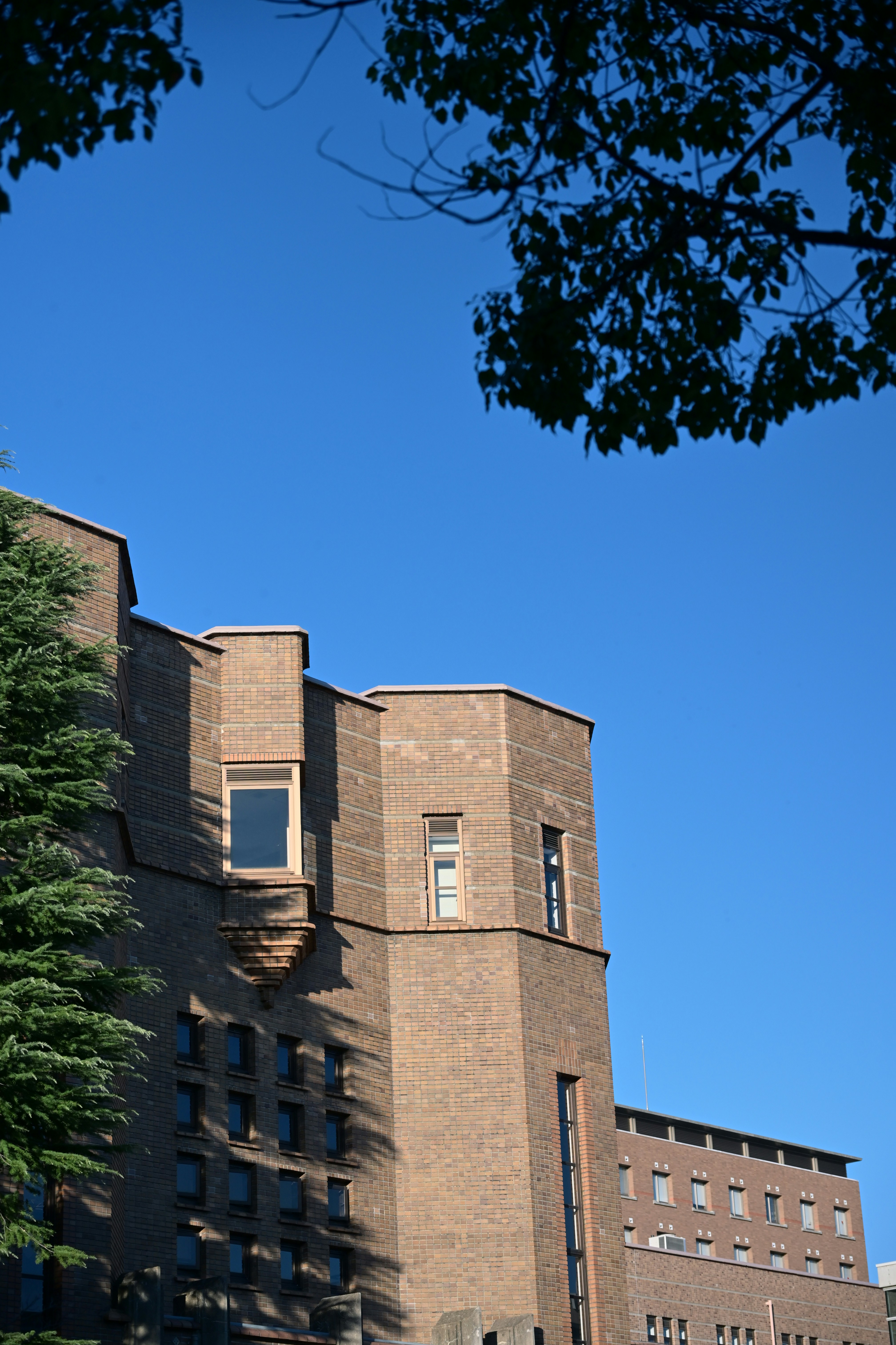A brick building with trees against a blue sky.