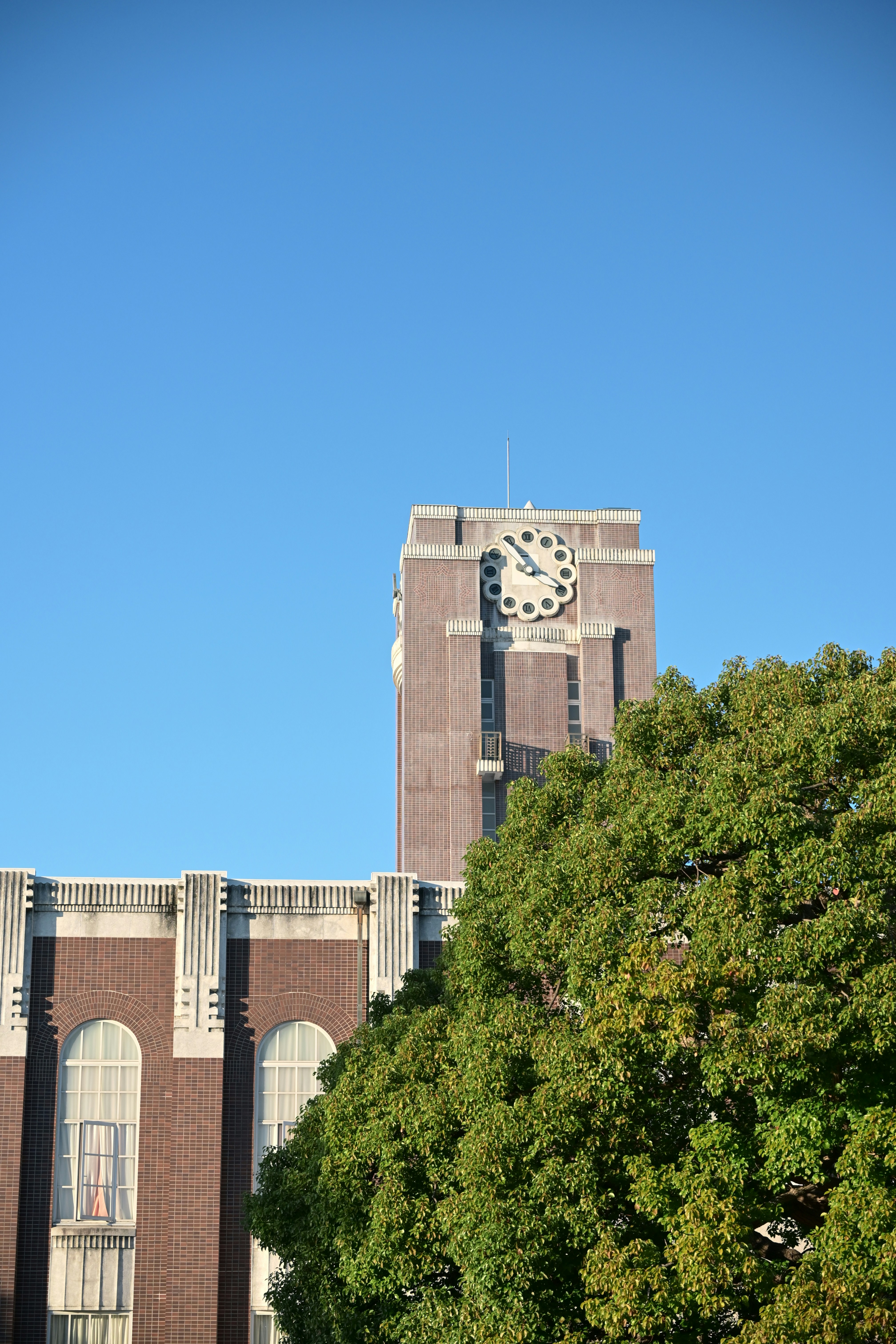 Brick building with clock tower against clear blue sky.